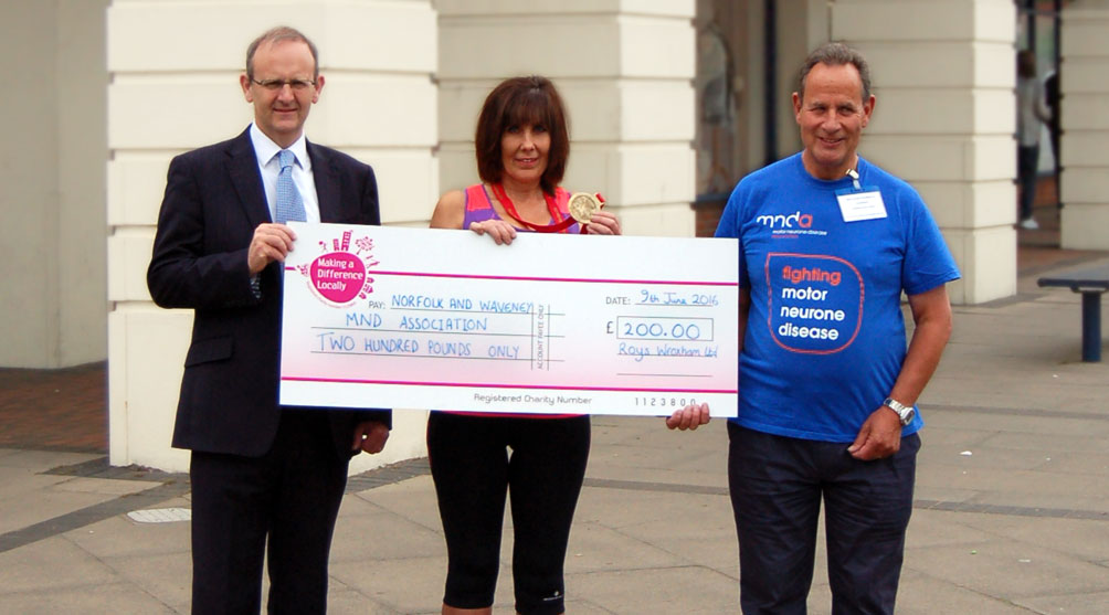 Ed Roy (managing Director) and Karen Grapes (Roys Dereham store manager) presenting a cheque to Malcolm Chubbock (Chairman of the local MND branch)